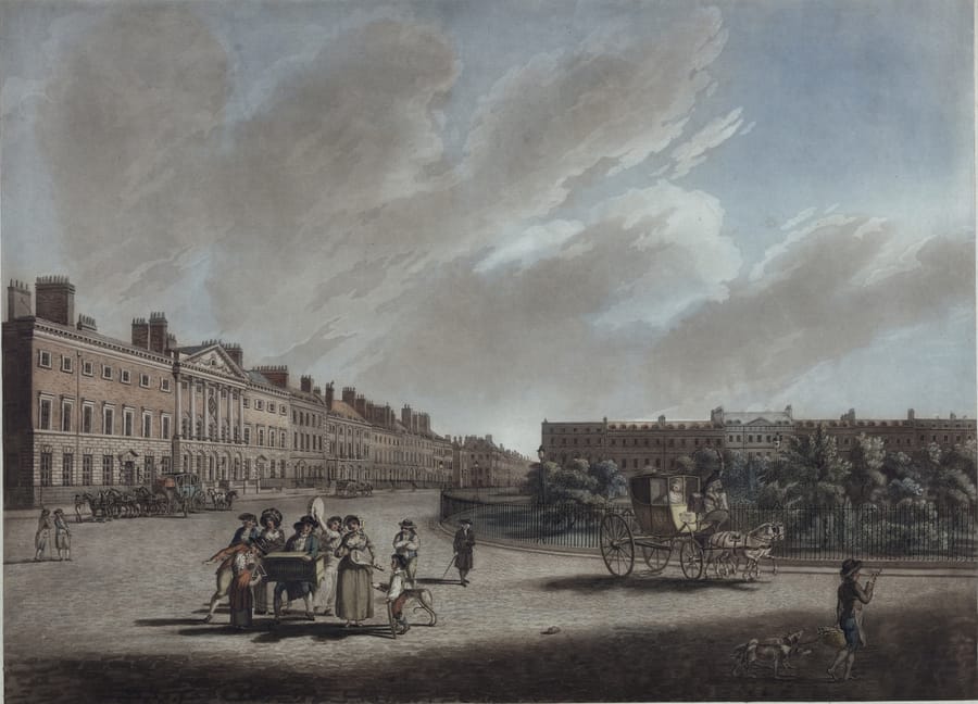 A wide Georgian square seen from one corner under a high grey sky. A long uniform brick terrace with a pedimented centre block runs down the left side, a second terrace closes the far end, and the railed garden fills the right with mature trees. A horse-drawn carriage crosses in front of the railings, a group in eighteenth-century dress stands around a street vendor's barrow in the foreground, and a boy with a basket walks two dogs at the right.